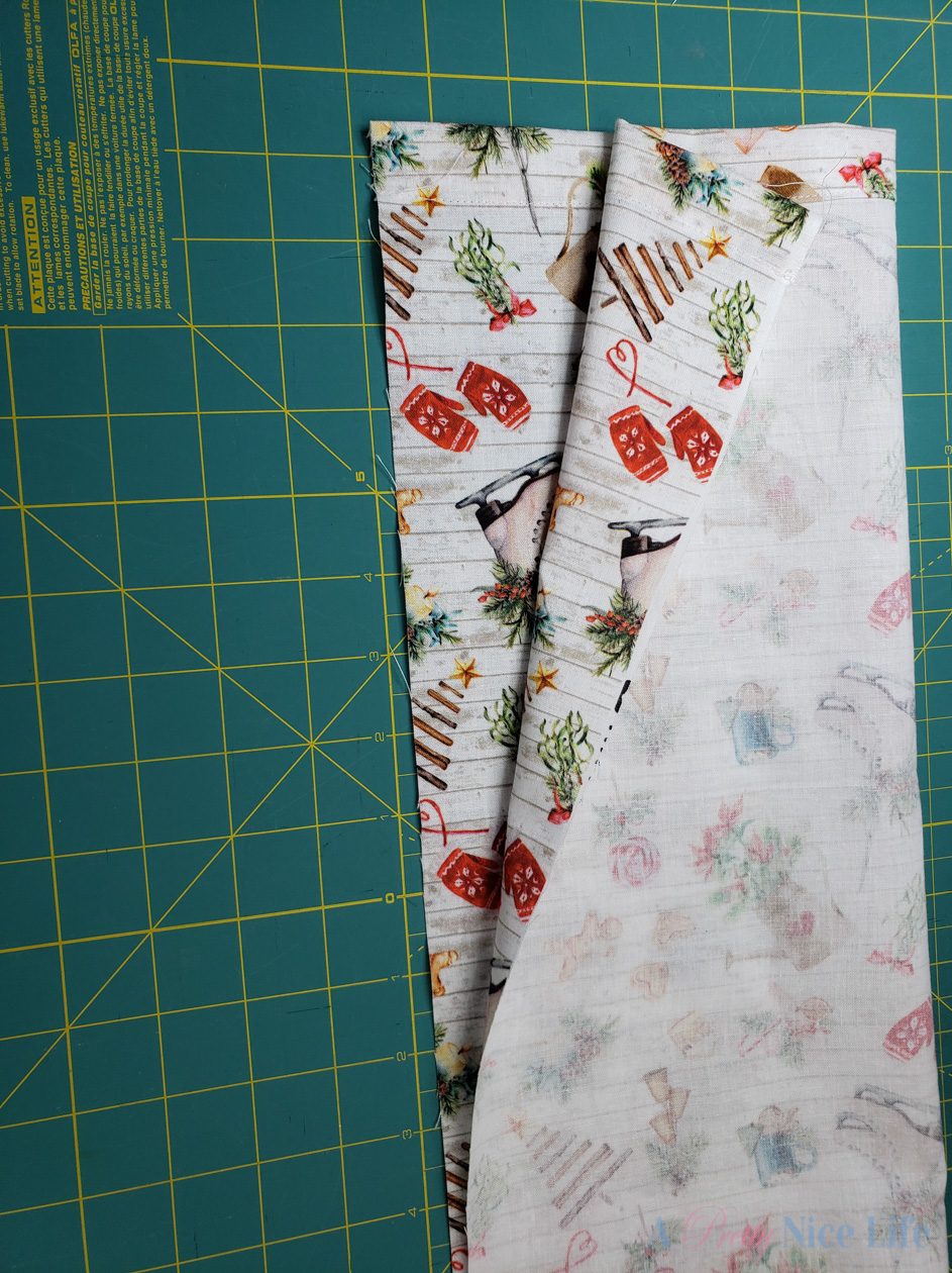 Prepare to sew the length of your plastic grocery bag holder by folding your hemmed fabric rectangle in half lengthwise