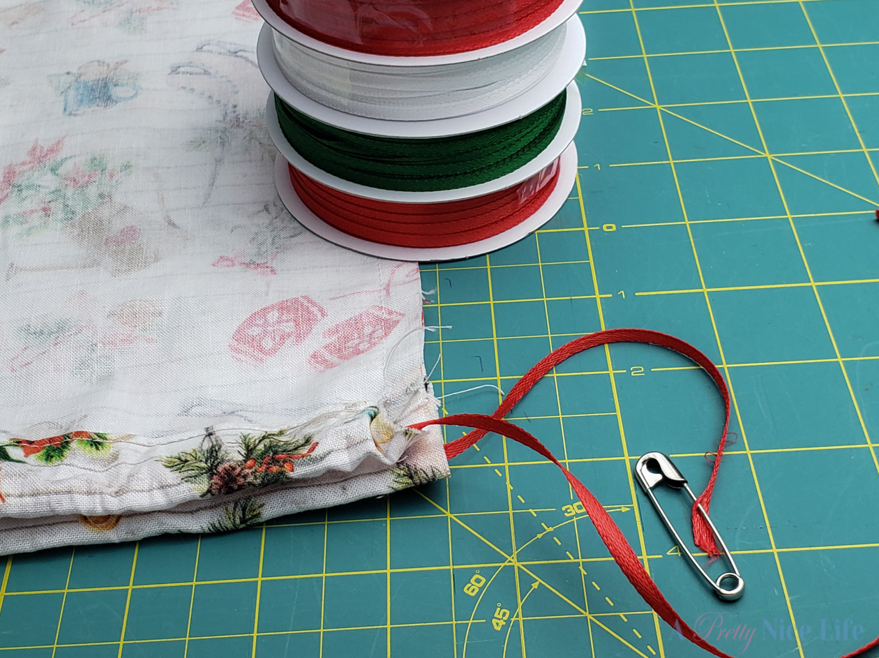 thread ribbon through top casing of fabric plastic bag dispenser