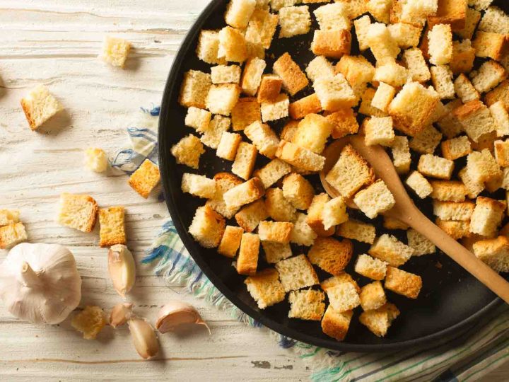 homemade croutons toasting in a skillet with fresh garlic bulb nearby