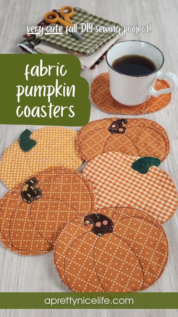 Six quilted fabric pumpkin coasters on a wood table with a coffee cup resting on one. Fall fabric scraps and small scissors are visible in the background. Text reads: "VERY CUTE Fall DIY Sewing Project! Fabric Pumpkin Coasters Aprettynicelife.com"