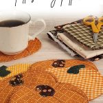Six quilted fabric pumpkin coasters on a wood table with a coffee cup resting on one. Fall fabric scraps and small scissors are visible in the background. Text reads: "Pumpkin Coasters. Fall Sewing Pattern. Aprettynicelife.com"