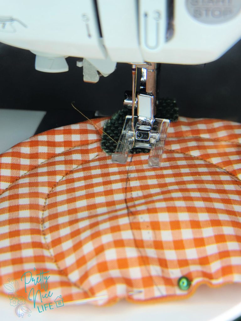 Machine quilting the rib lines on a fabric pumpkin coaster with contrasting thread to define the pumpkin sections