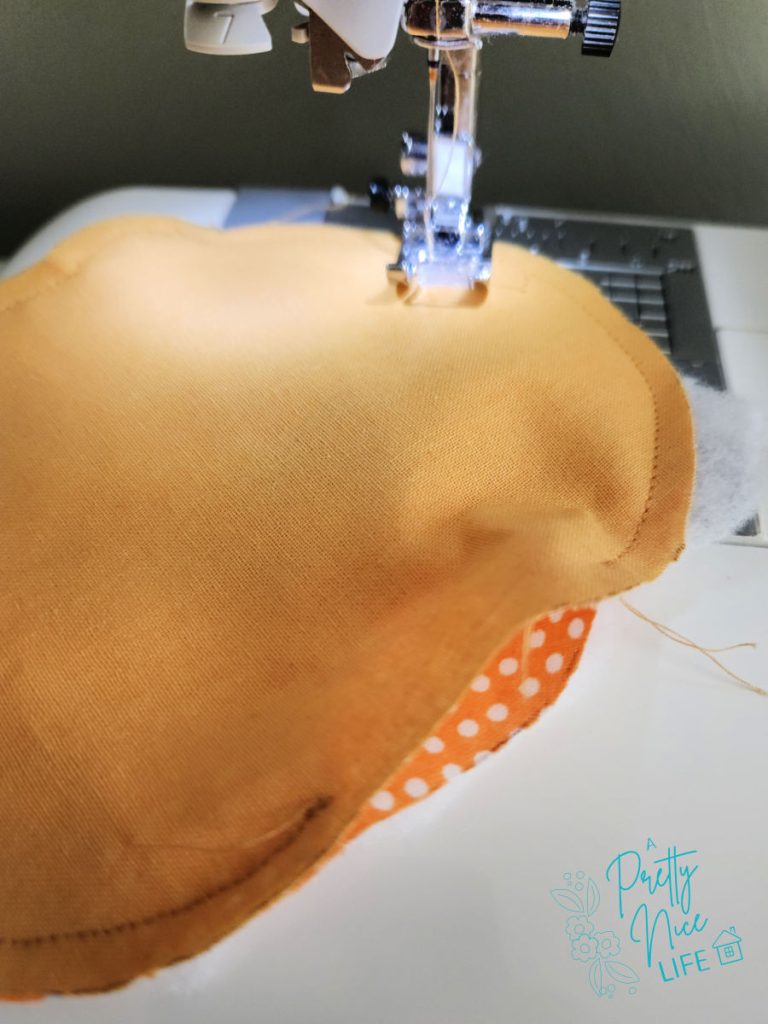 Sewing around the curved edge of a fabric pumpkin coaster at the sewing machine with right sides together