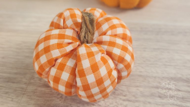 Cute plush stuffed fabric pumpkin in orange gingham fabric with twine stem