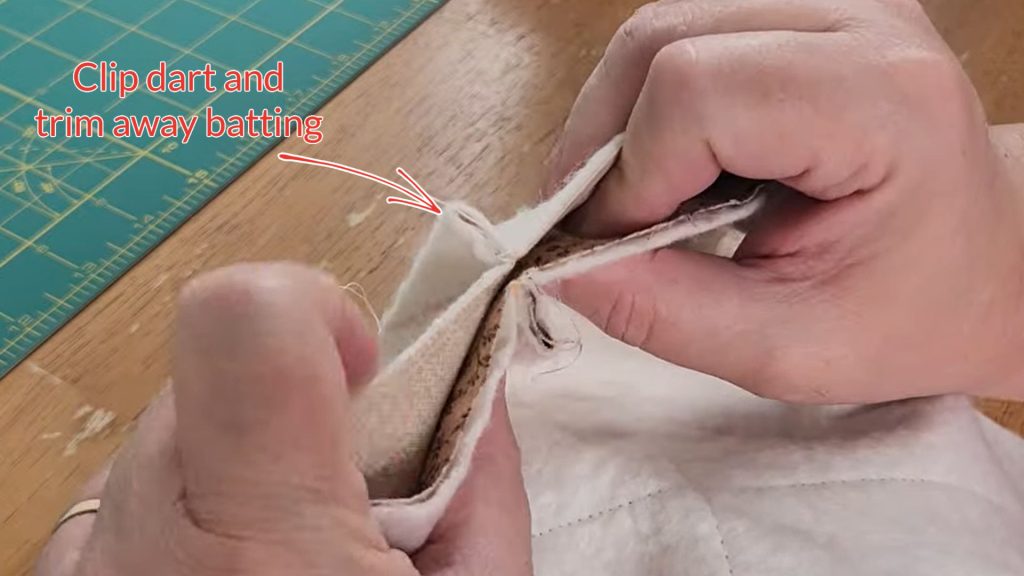 two layers of bowl cozy, right sides together, darts matching. text with an arrow points to the darts and says "clip dart and trim away batting"