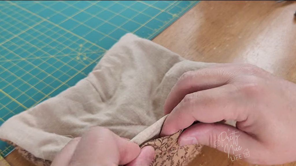 fingers folding in seam allowance of opening to prepare for final sewing